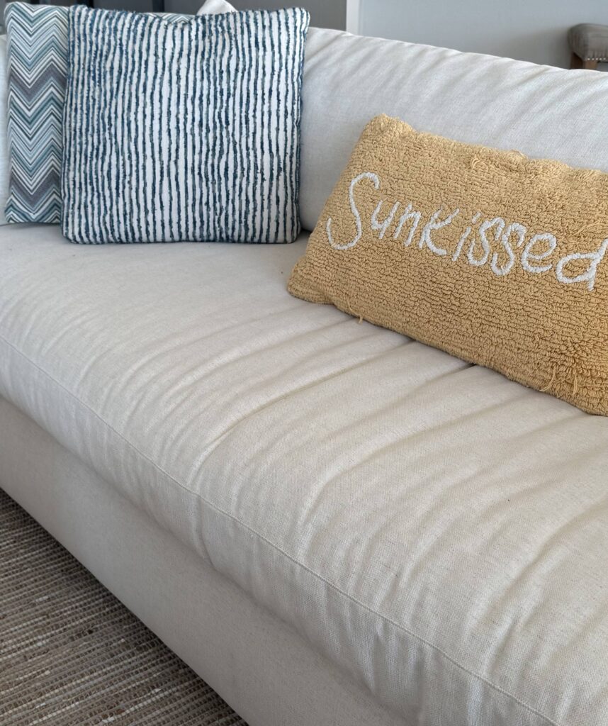 image of a white sofa with a yellow pillow that says sunkissed